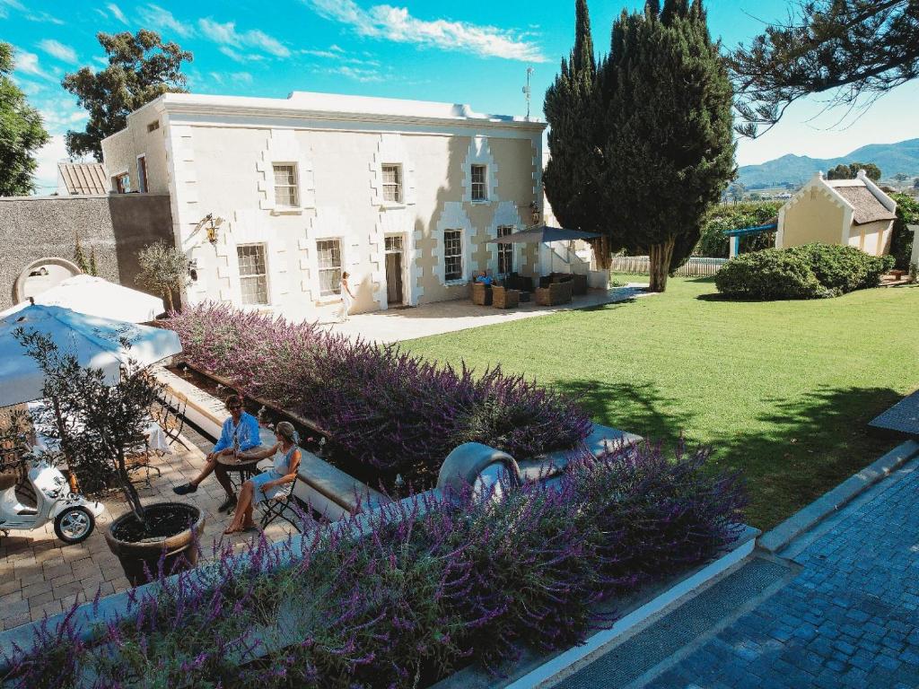 a man sitting on a bench in front of a house at Paul René Manor House in Robertson