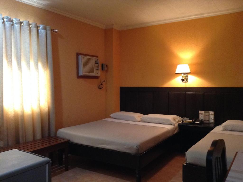 um quarto de hotel com duas camas e uma janela em Miami Inn em Cagayan de Oro