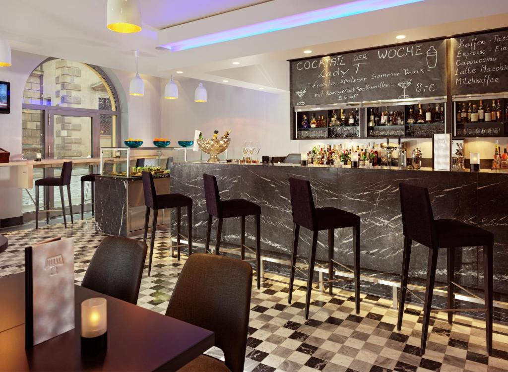 a bar in a restaurant with black chairs and tables at HYPERION Hotel Dresden Am Schloss in Dresden