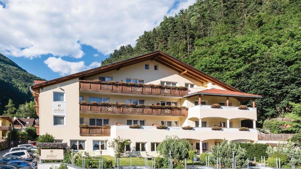 een groot gebouw met balkons aan de zijkant van een berg bij Saldur Small Active Hotel in Sluderno