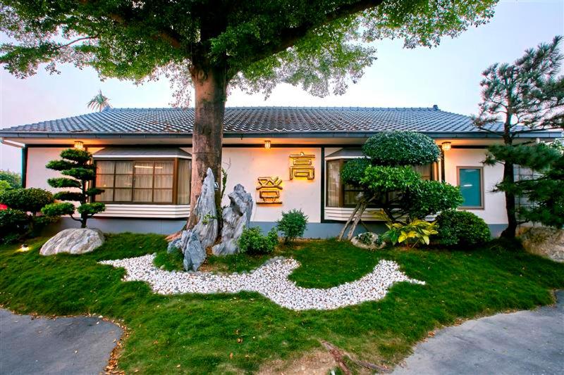 ein Haus mit einem Baum im Vorgarten in der Unterkunft Gold Motel in Puxin