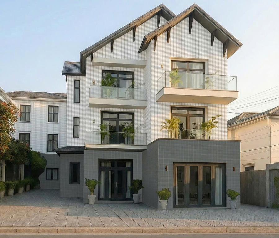 a large white building with plants in front of it at Hila Hotel Vạn Ninh in Vạn Ninh