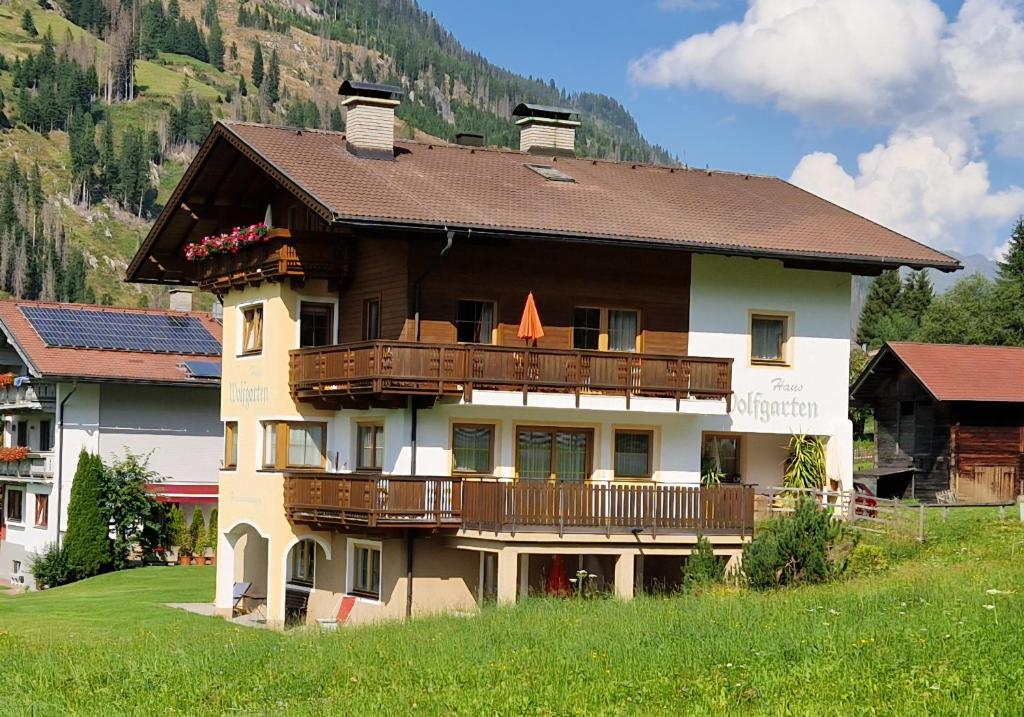 a large building with a balcony and a mountain at Gästehaus WOLFGARTEN in Sankt Jakob in Defereggen