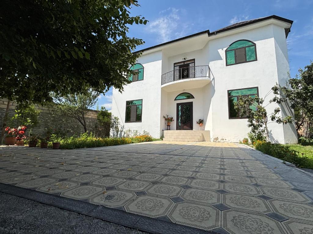 a large white house with a driveway at Gunluk ev in Sheki