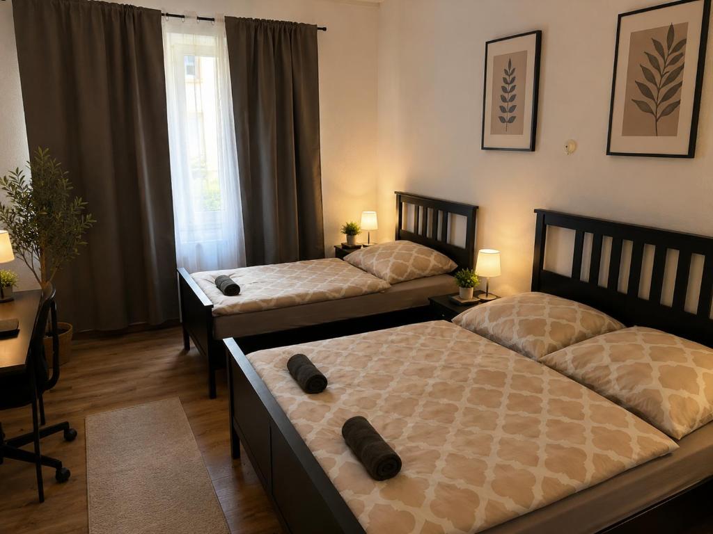 a bedroom with two beds and a desk at Central Rooms Hauptbahnhof Koblenz in Koblenz