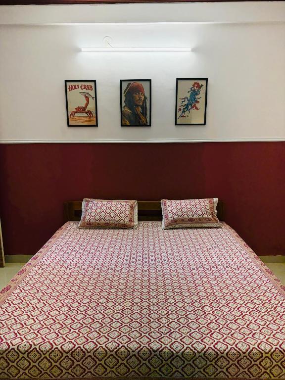 a large bed in a room with four pictures on the wall at Turtlenest by the Beach in Morjim