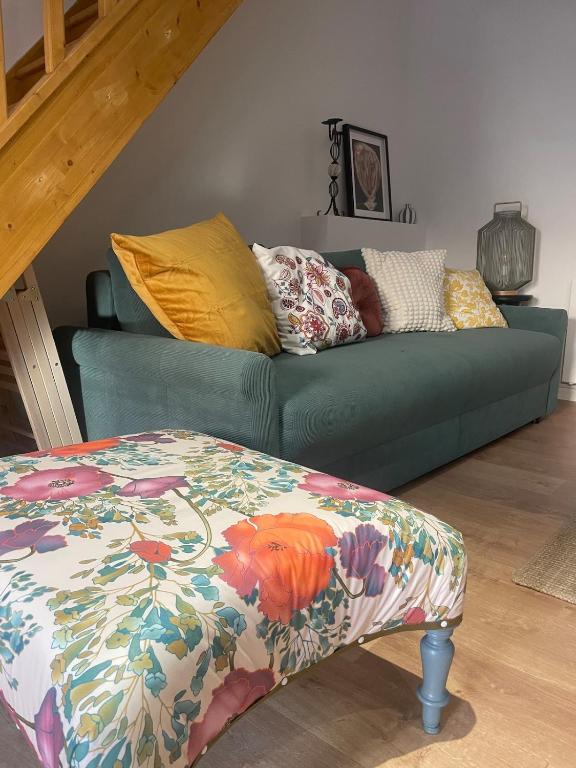 a green couch in a living room with a bed at Le cottage à la glycine - Maison de charme au cœur des gorges de la Loire in Chambles