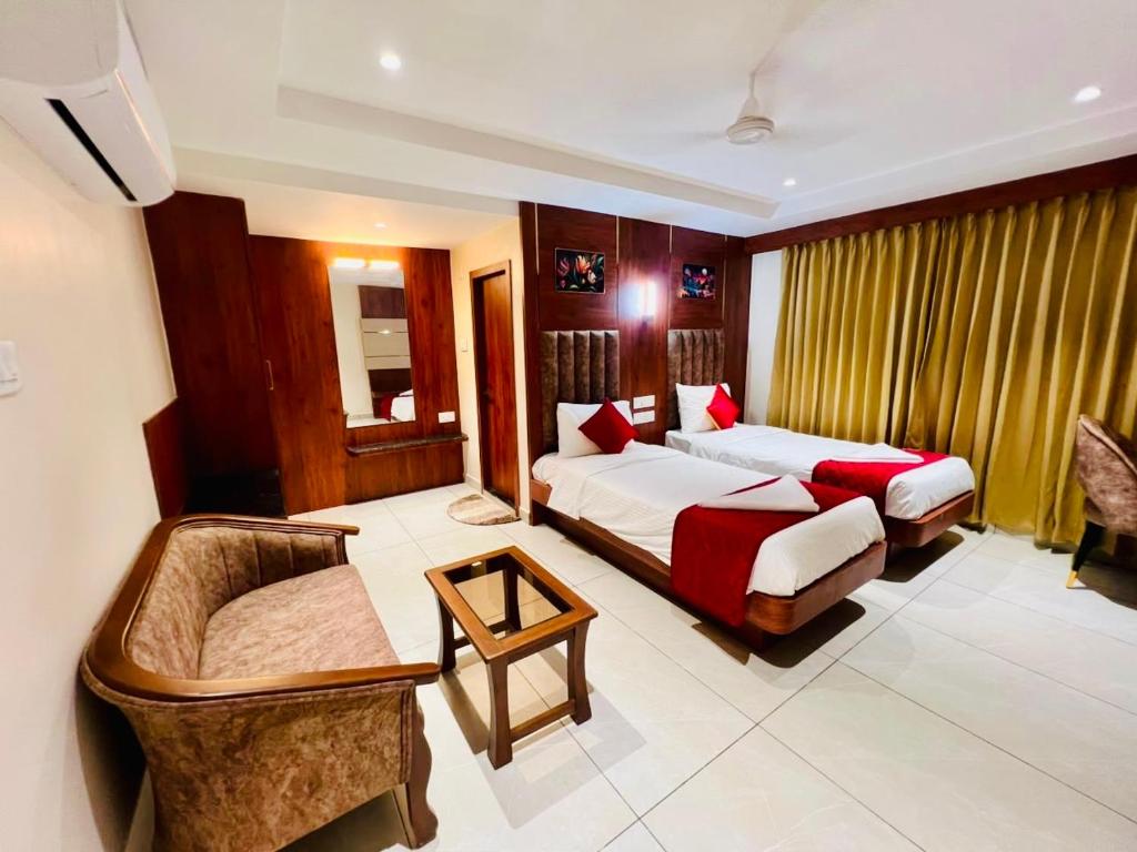 a hotel room with two beds and a couch at Sri Vishnu Grand in Vellore
