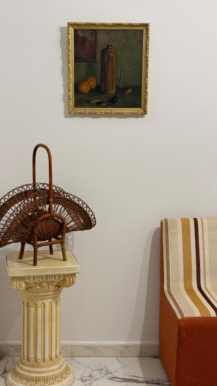 a wicker chair sitting on a table next to a painting at Villa Korba 1st Floor in Korba