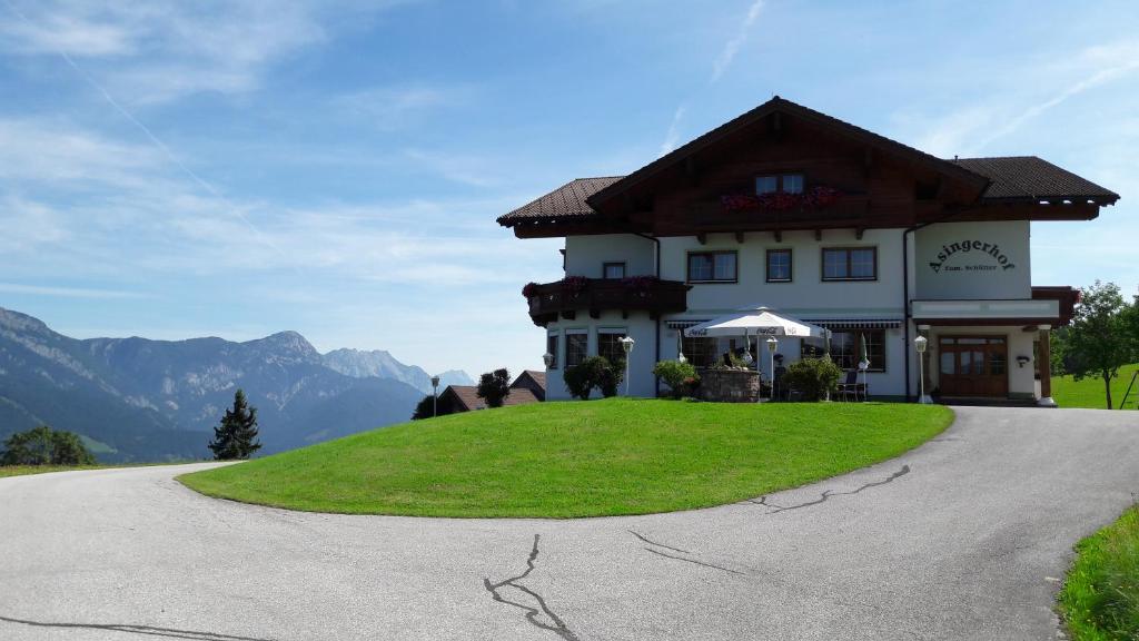 a house on top of a grassy hill at Hotel-Pension Asingerhof in Schladming