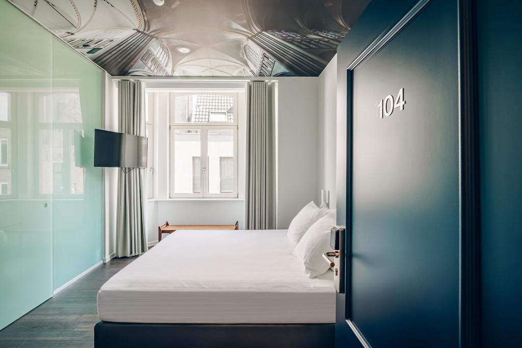 une chambre avec un lit blanc et une fenêtre dans l'établissement ROMY BRUGES Historic Centre, à Bruges