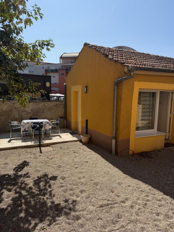 a yellow house with a table and chairs next to it at Gîte Le lys 2 à 4 personnes in Colmar