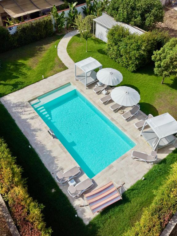 an overhead view of a swimming pool with chairs and umbrellas at Luxury B&B Coccolhouse in San Cesario di Lecce