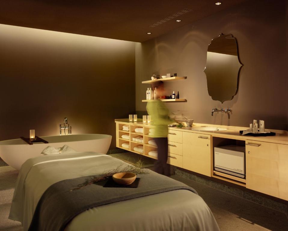 a woman in a bathroom with a tub and a sink at HYPERION Hotel Dresden Am Schloss in Dresden
