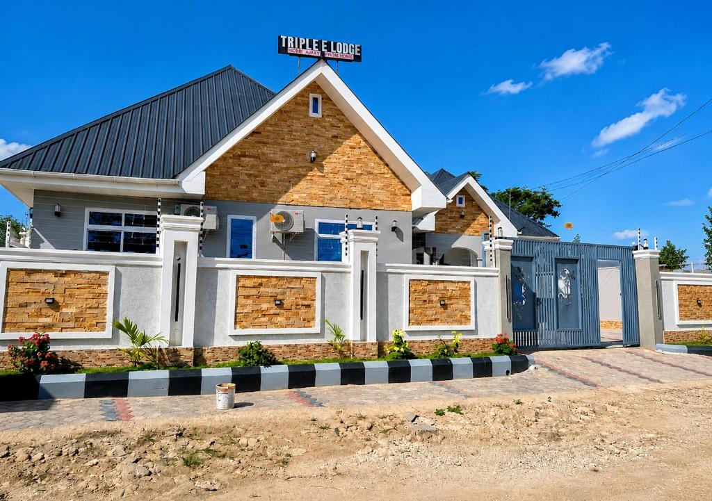 a house with a garage in front of it at Triple E Lodge Kibaha in Kibaha