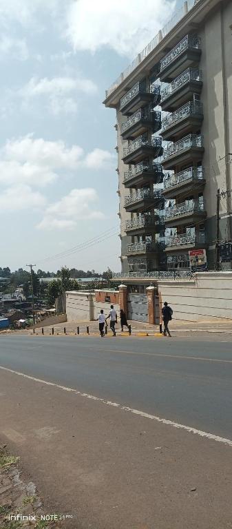 a group of people walking down a street in front of a building at 1 bedroom BNB Meru in Meru