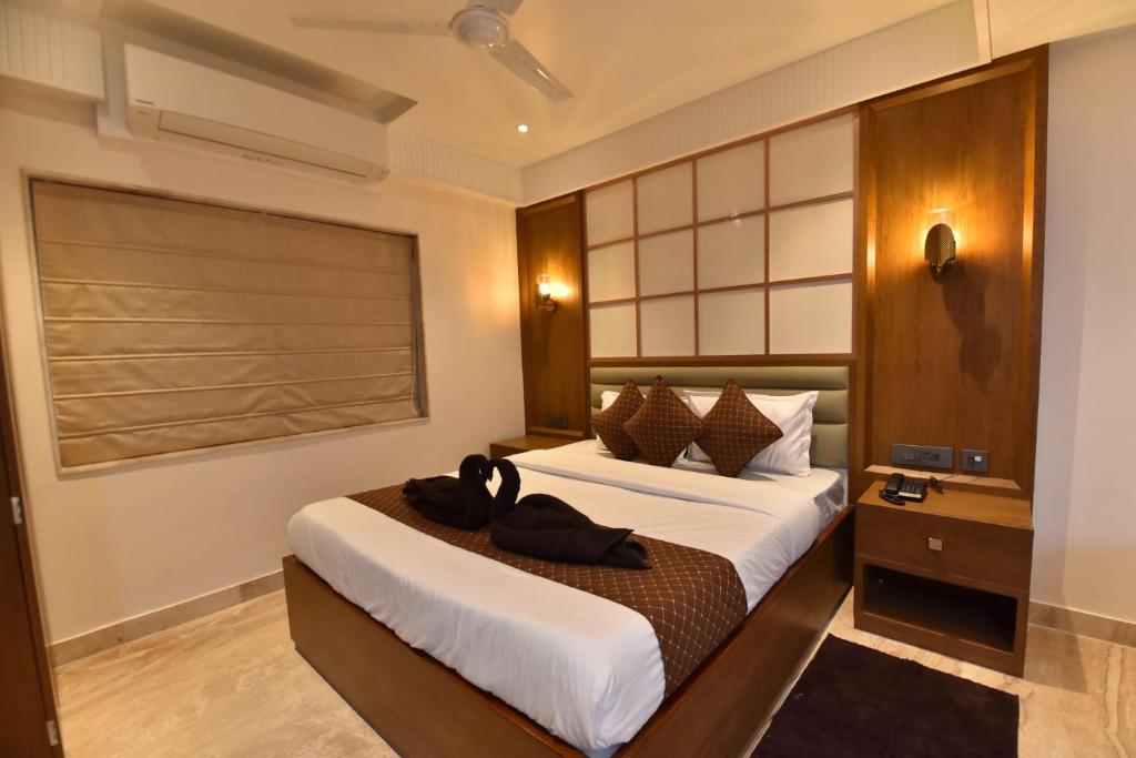 a bedroom with a bed with two black shoes on it at Eennra Ssubarna in Baharampur
