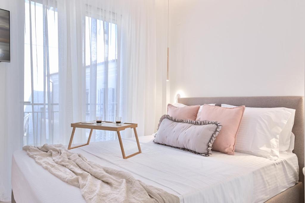 a white bedroom with a bed with a table on it at Elan Suites Preveza in Preveza