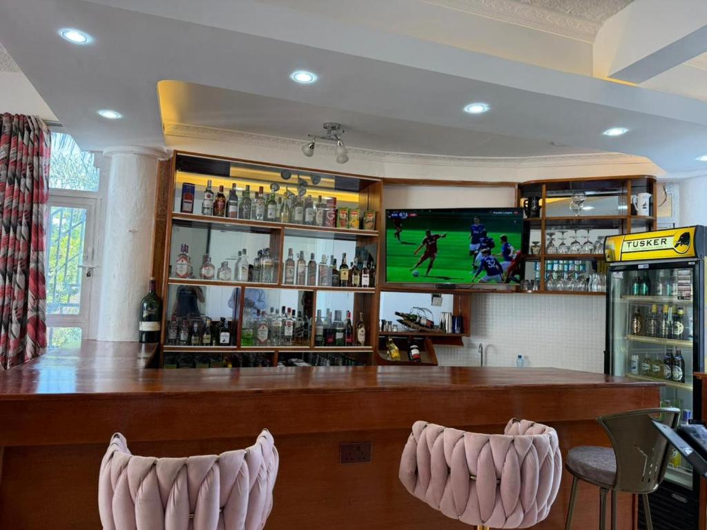 a bar with two chairs and a television on the wall at Stardom Hotel in Nairobi