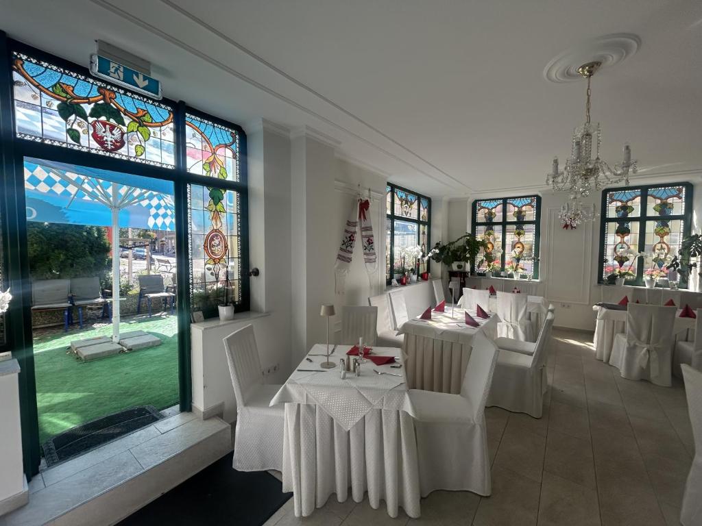 a dining room with white tables and chairs and a stained glass window at DREI SEEN HOTEL BRANDENBURG in Lindow Ratskeller in Lindow