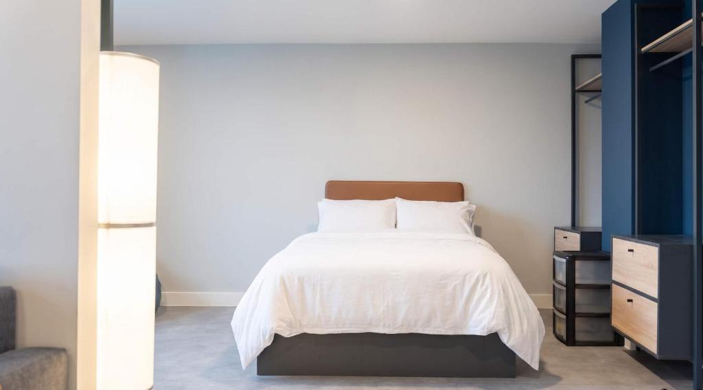 a bedroom with a white bed with a wooden headboard at Student Only Studio in Central Loughborough in Loughborough