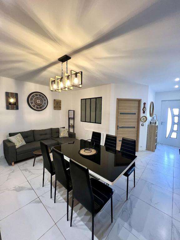 a dining room and living room with a black table and chairs at Le Gustave - Proche ville in La Rochelle