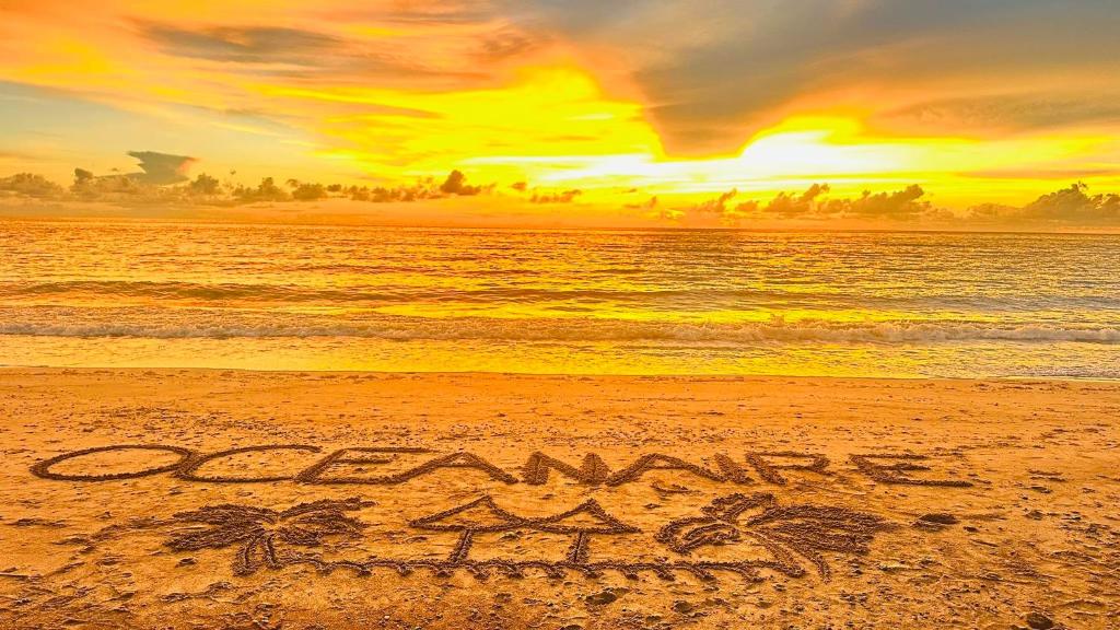 a sign written in the sand on the beach at Oceanaire Beach Resort ELYU in Bacnotan