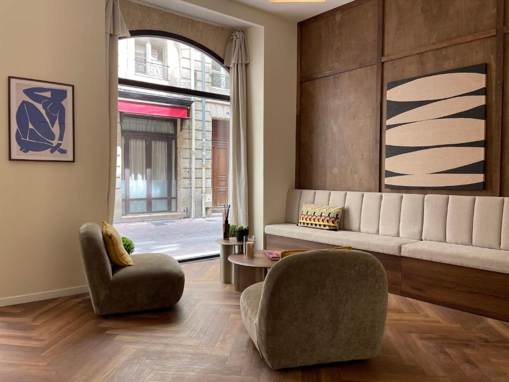 a living room with a couch and a chair at Hôtel du Théâtre - Hypercentre - Climatisé in Bordeaux