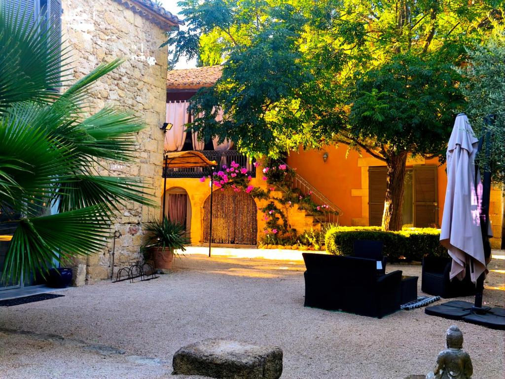 a patio with a white umbrella and a building at Maison d'hôte Mas de Castille entre Uzès et le pont du Gard in Argilliers