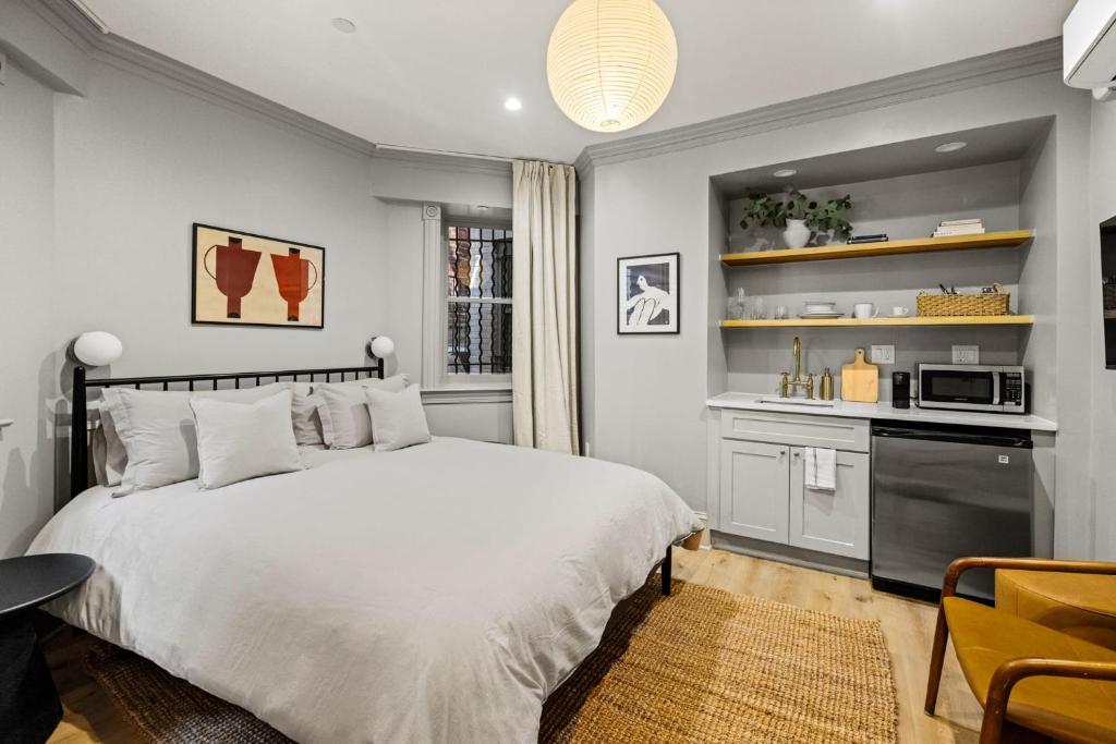 a bedroom with a white bed and a kitchen at Suite 1B at Maison Dupont a Dupont Circle Inn in Washington, D.C.