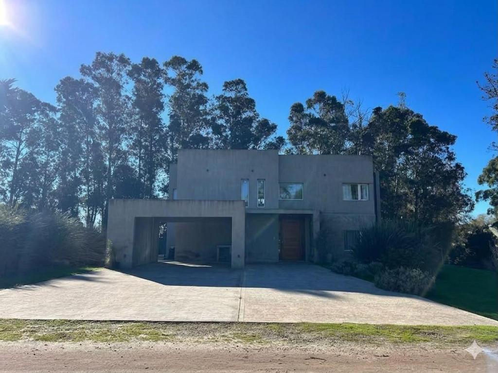 a large building with a garage in front of trees at Casa Benito - Barrio Privado con Piscina en Chapadmalal in Mar del Plata