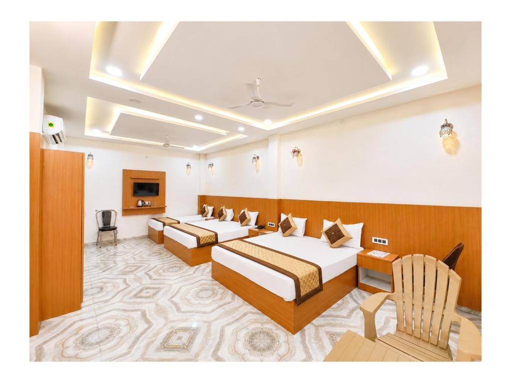 a hotel room with two beds and a tv at निर्मला पैलेस अयोध्या राम मंदिर - Hotel The New Nirmala Palace Ayodhya Near-Ram-Janmabhoomi-and-Ayodhya-Ram-Mandir-with-parking-and-Restaurant-Facilities - Best Hotel In Ayodhya in Ayodhya