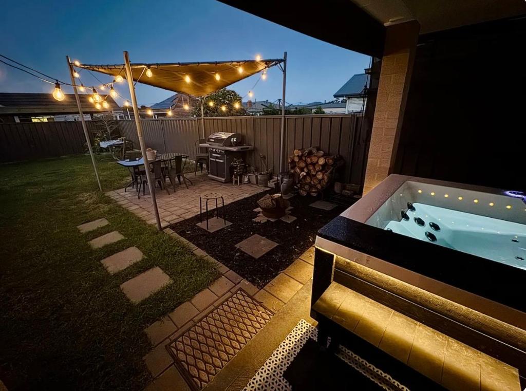 a backyard with a hot tub and a grill at Maitland Getaway - Spa, EV Friendly, Pet Friendly in Telarah
