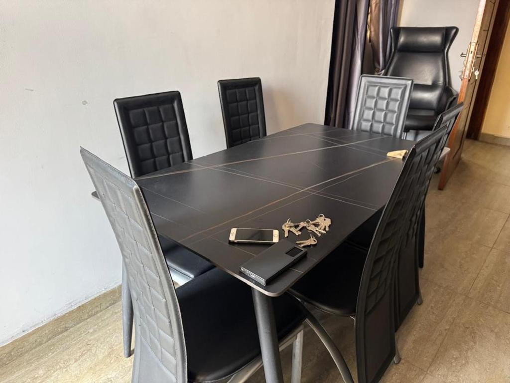a black table and chairs with a purse on it at Cozy home with a generator and Wi-Fi in Kinshasa