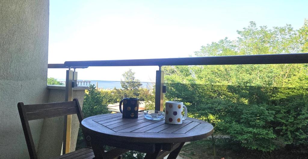 a wooden table with two mugs on a balcony at Sun Sea 3 sea view in Shkorpilovtsi