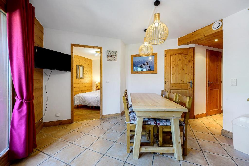 a dining room with a table and a bedroom at Les Ancolies Benelli in Les Menuires