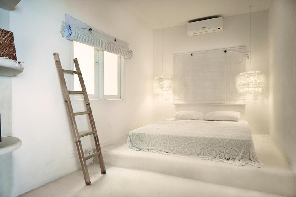 a white bedroom with a ladder and a bed at Sal Secret Spot in Uluwatu