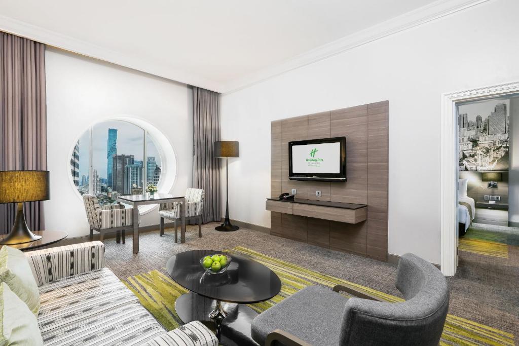 A furnished sitting area with a television, sofa, armchair, and round skyline window.