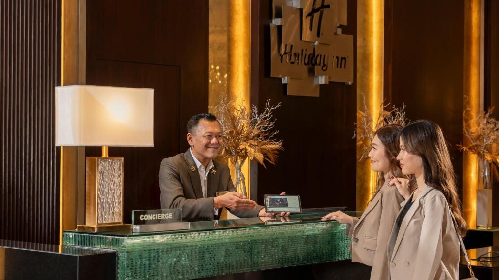 Guests are being assisted at a glossy concierge counter in the hotel lobby.