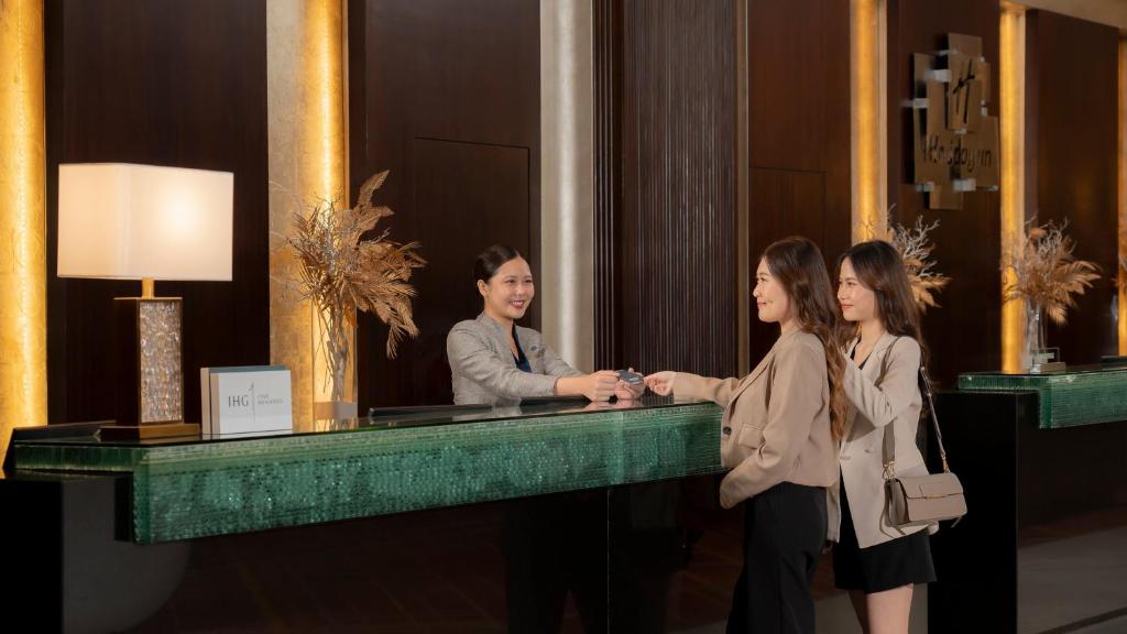 Two guests complete a welcome or check-in interaction across the hotel reception desk.