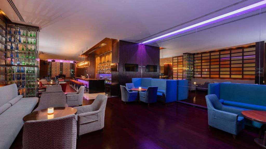A dimly lit hotel lounge with bar seating and clustered armchairs.