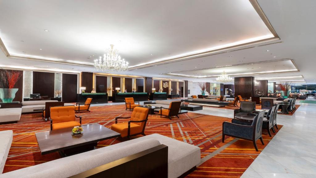 A large lobby offers sofas, armchairs and low tables across a richly patterned carpet.