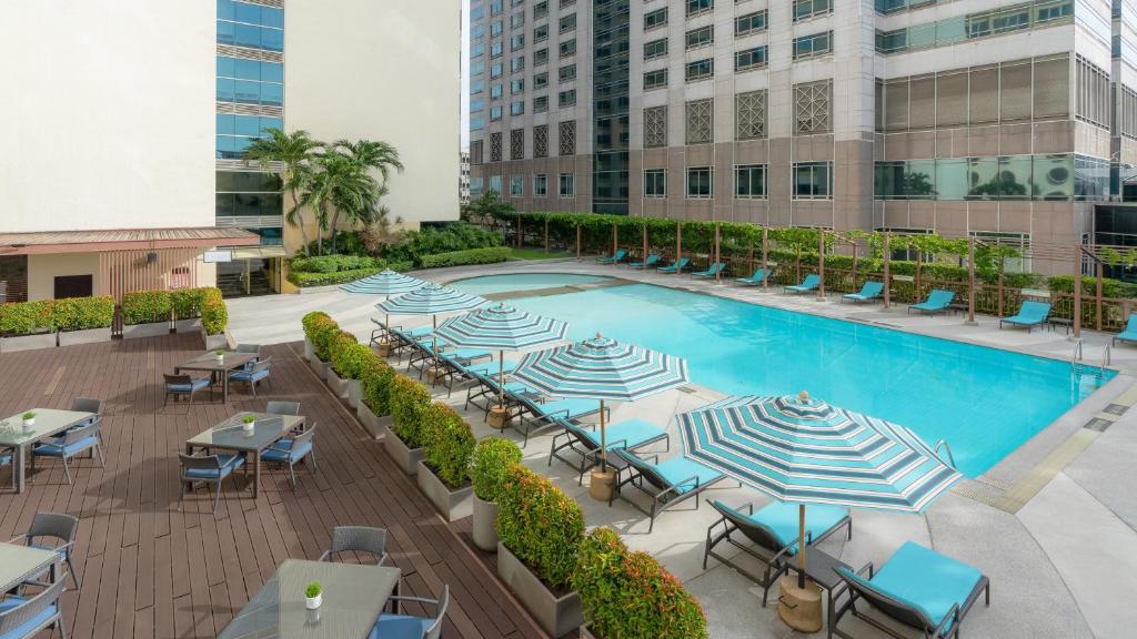 A wide view of the hotel pool, deck seating and surrounding city buildings.