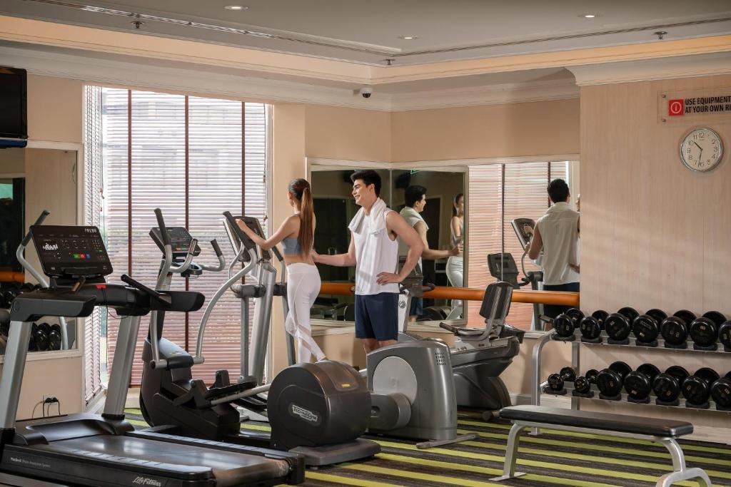 A bright hotel gym with cardio machines, free weights and mirrored walls.