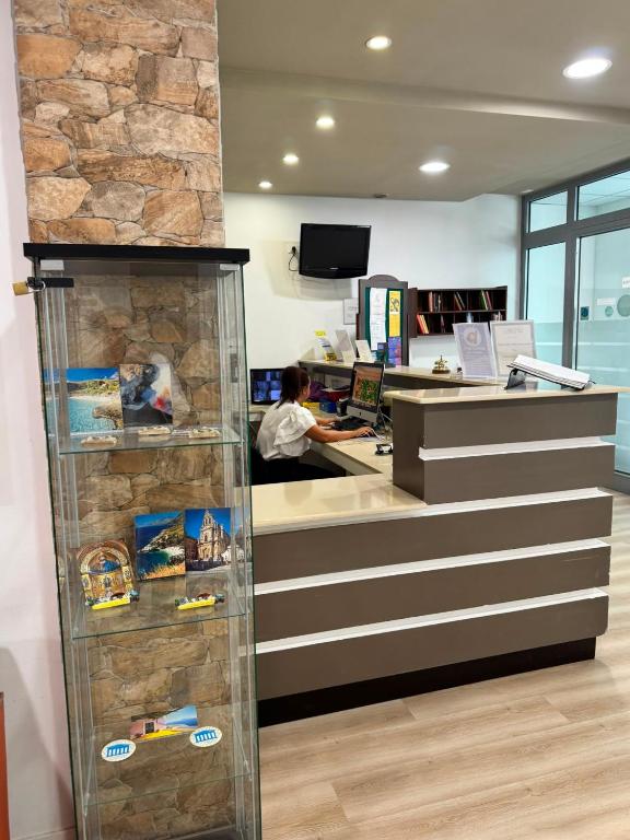 a counter in a store with a man sitting at a desk at Hotel Elite Palermo Centro in Palermo