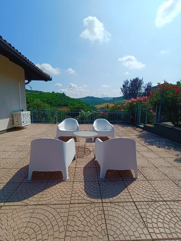 three white chairs and a table on a patio at La Casa del Merlo in Rodello