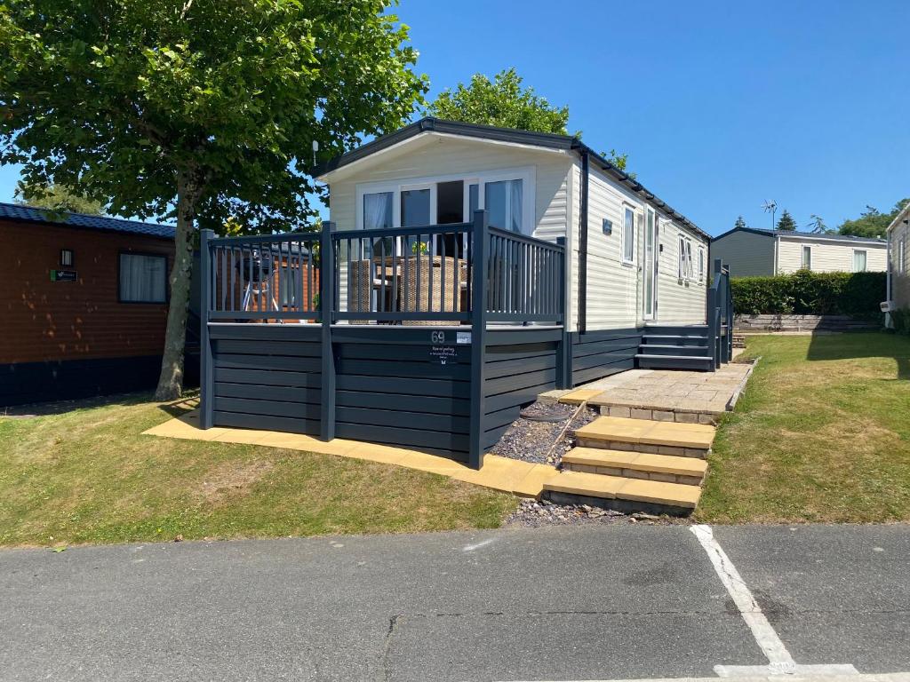 a tiny house with a porch and a deck at Caravan no 69 in Cwm-y-glo