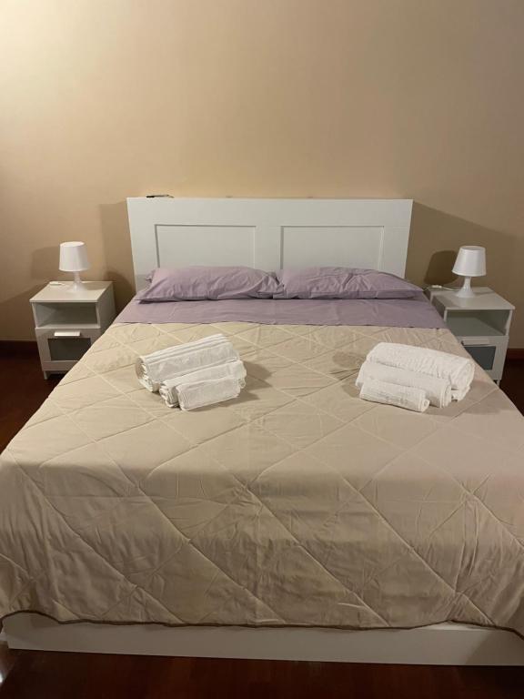 a bed with two towels on it with two night stands at la dimora del centro in Zafferana Etnea