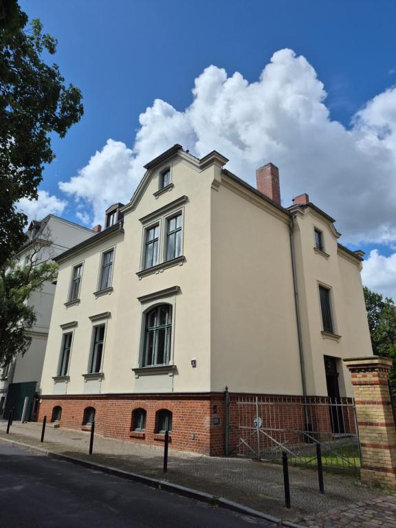 a white house on a street with a fence at PP Pension Potsdam in Potsdam