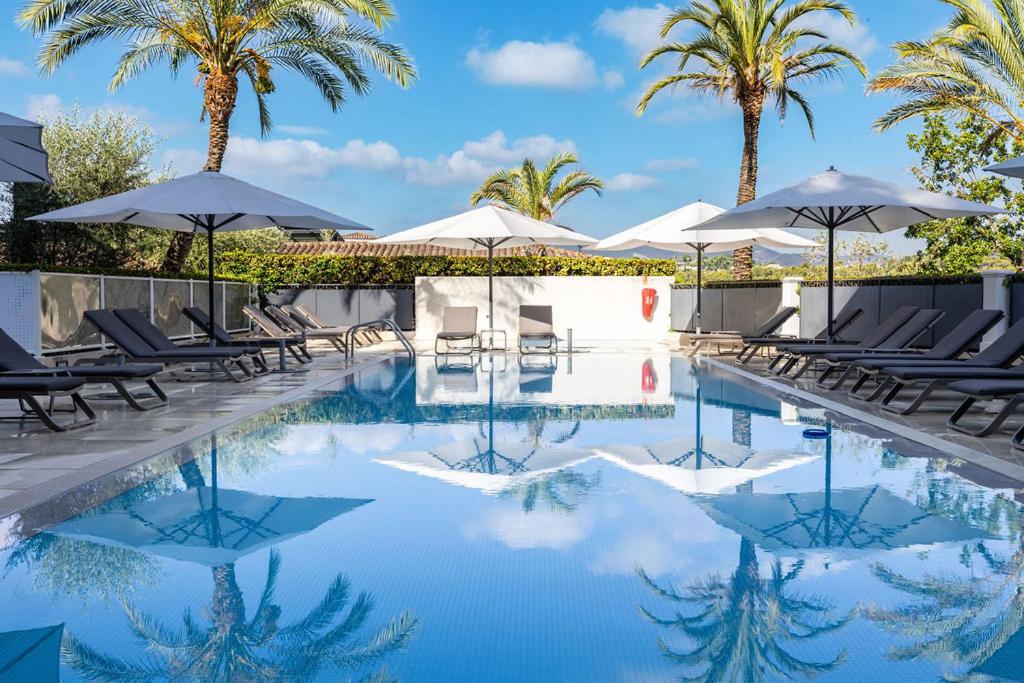 a pool with chairs and umbrellas and palm trees at Royal Mougins Golf, Hotel & Spa de Luxe in Mougins